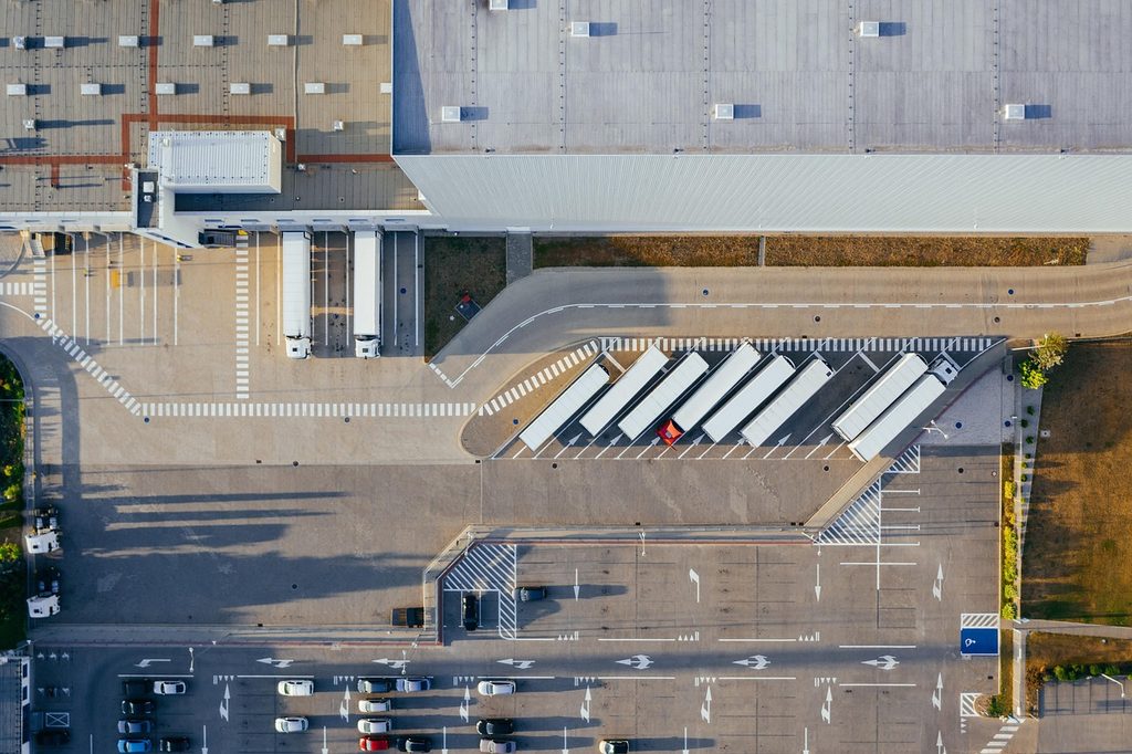 A line of trucks sits outside a production facility, ready to transport materials.